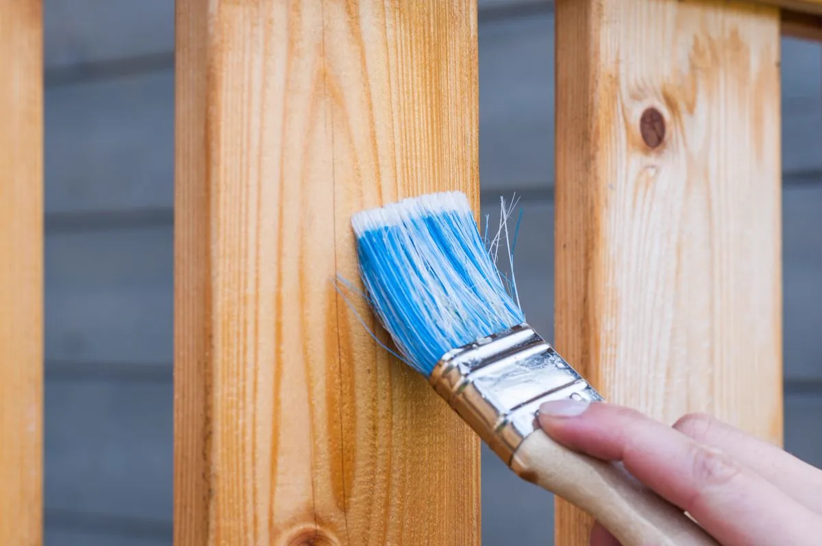 Brush applying finish to new fence pickets